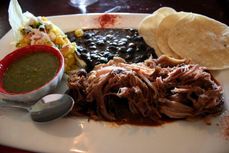 Pork carnitas with black beans, corn tamale, and green and red chile sauces