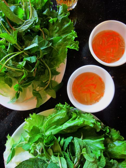 Bánh khọt and bánh xeo are wrapped with lettuce leaves and herbs, dipped in nuoc cham